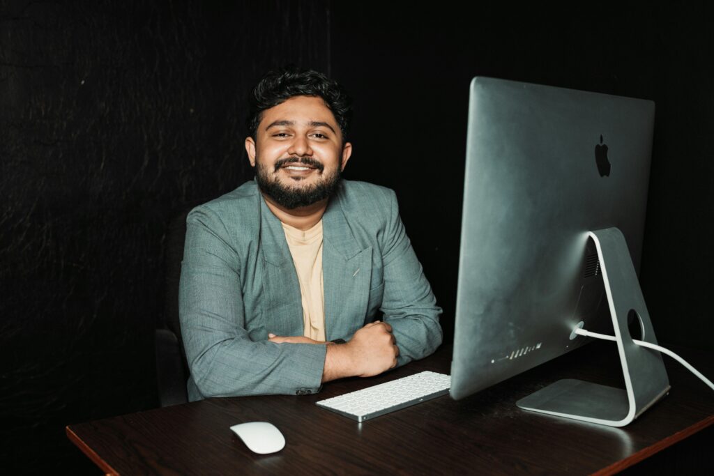 Confident businessman sitting at desk, working on computer in modern office.